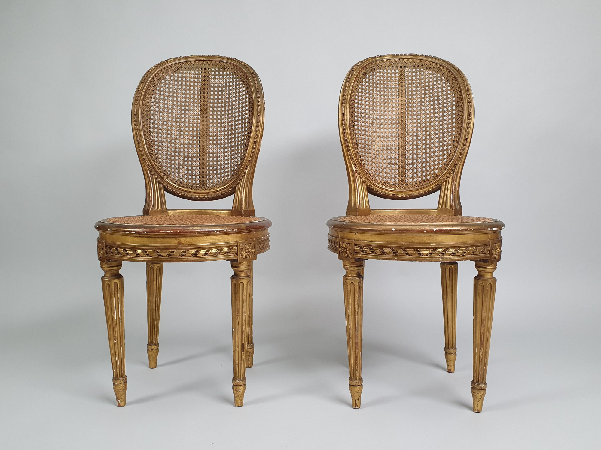 A pair of antique French caned bergère medallion back gilt Salon Chairs, in the style of Louis XVI 